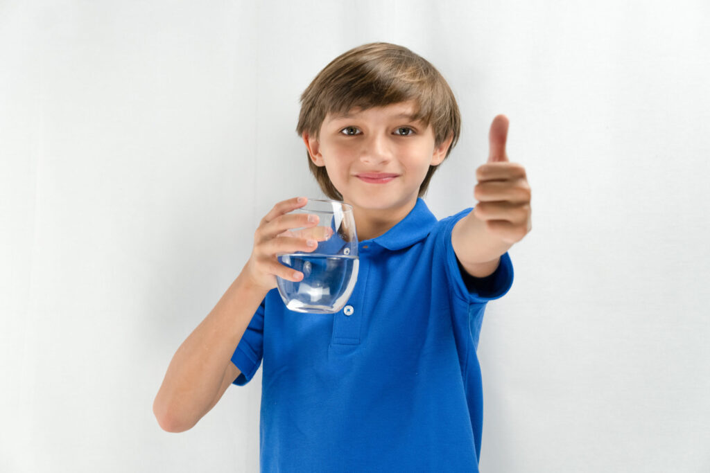 happy young boy drinking clean water from Water Filtration System
