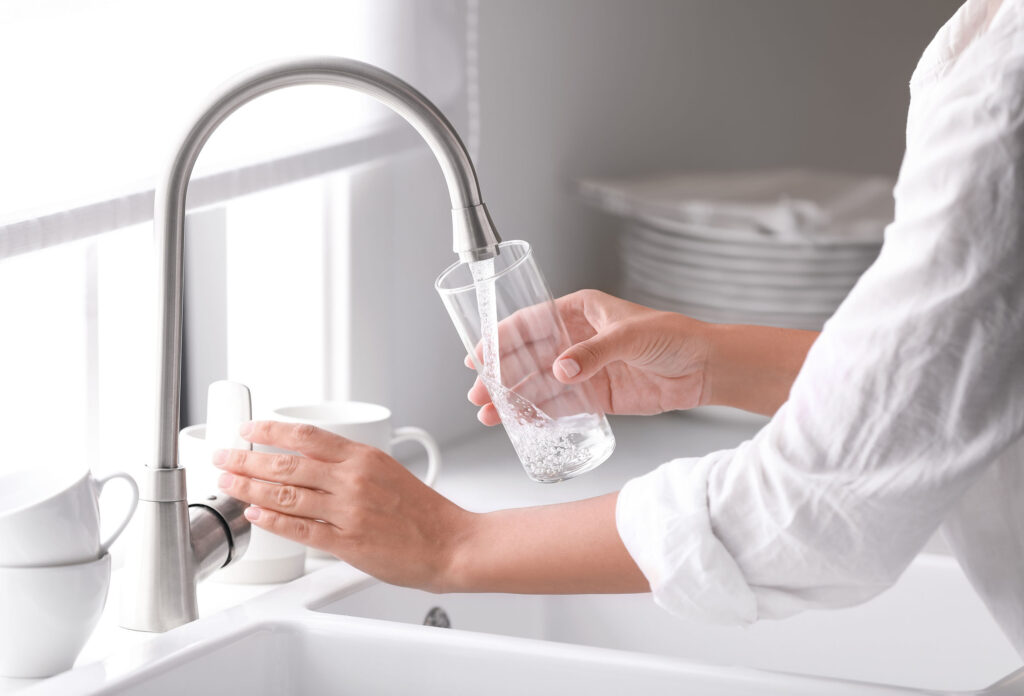 Person filling a glass of water - Water testing concept image
