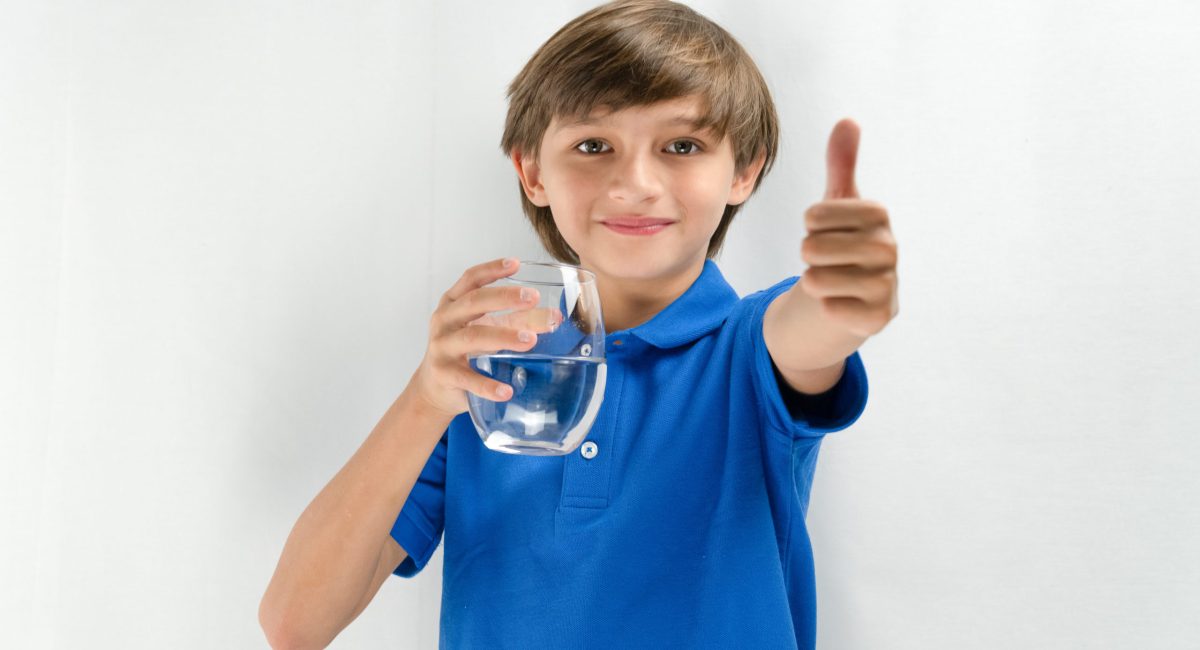 happy young boy drinking clean water from Water Filtration System
