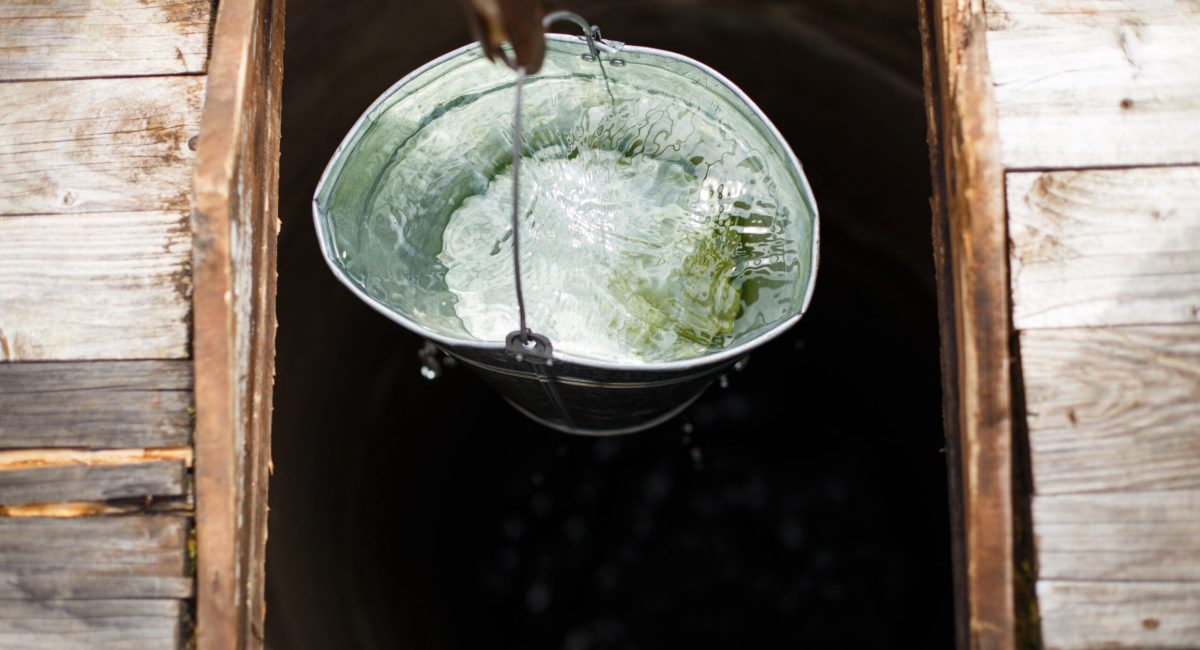 Blue bucked inside water well. water well with an old iron bucket