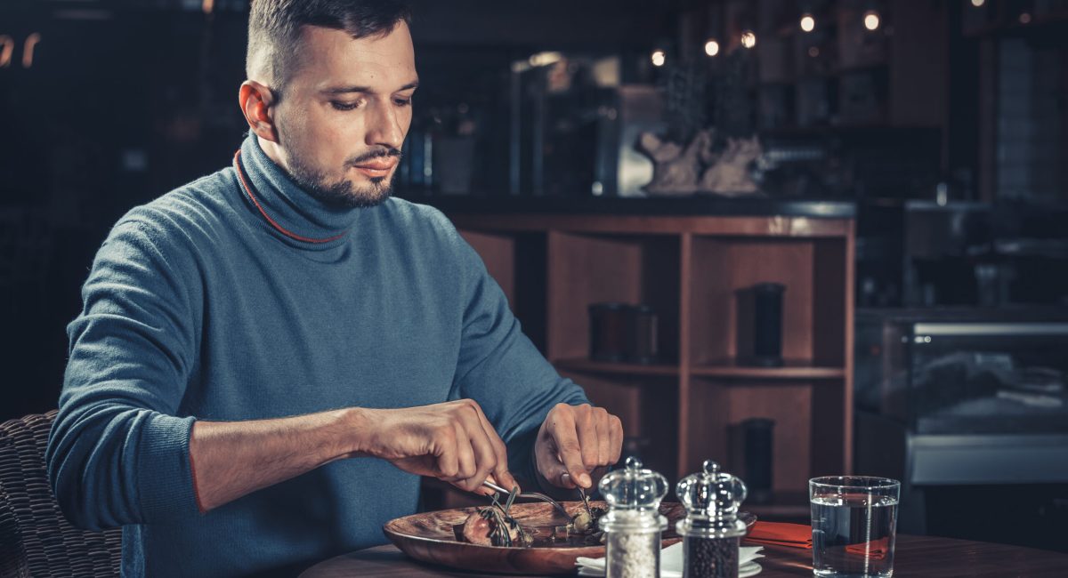 Young handsome man eating at the restaurant
