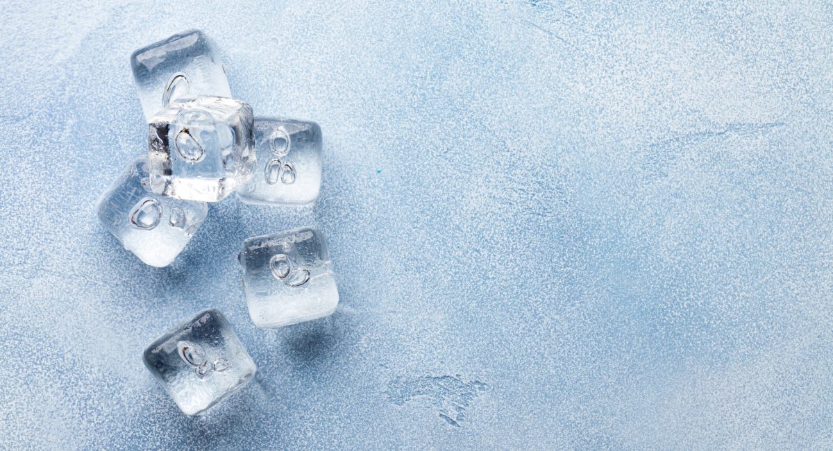 Ice cubes and water drops on stone background. Top view flat lay with copy space