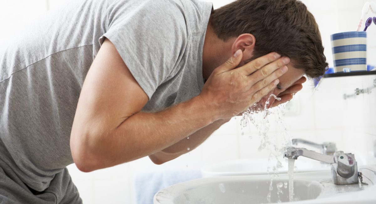 Man Washing Face In Bathroom Sink