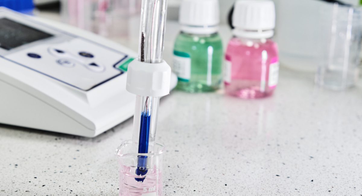 pH meter with glass electrode for measuring of alkalinity and acidity with calibration solution on the background. Analytical or electro chemistry laboratory.